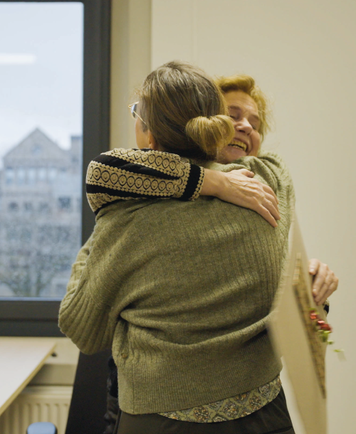 Mirjam knuffelt collega Heike die haar een kerstwens overhandigd